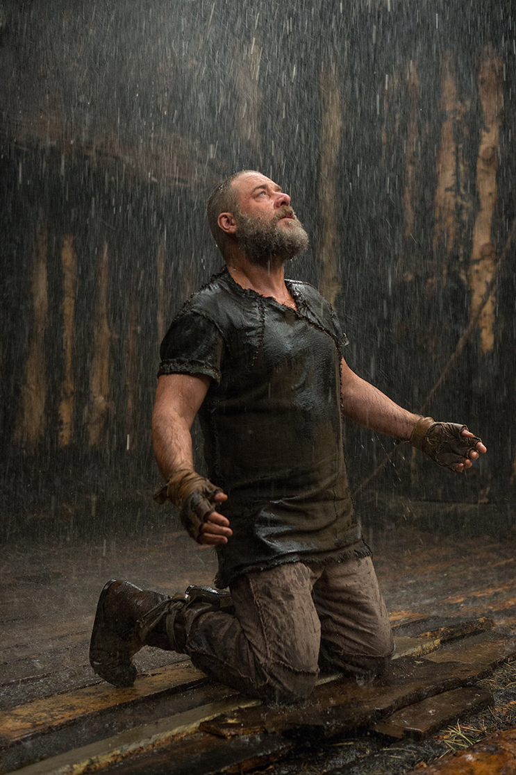 Noah kniet im Regen und blickt in den Himmel